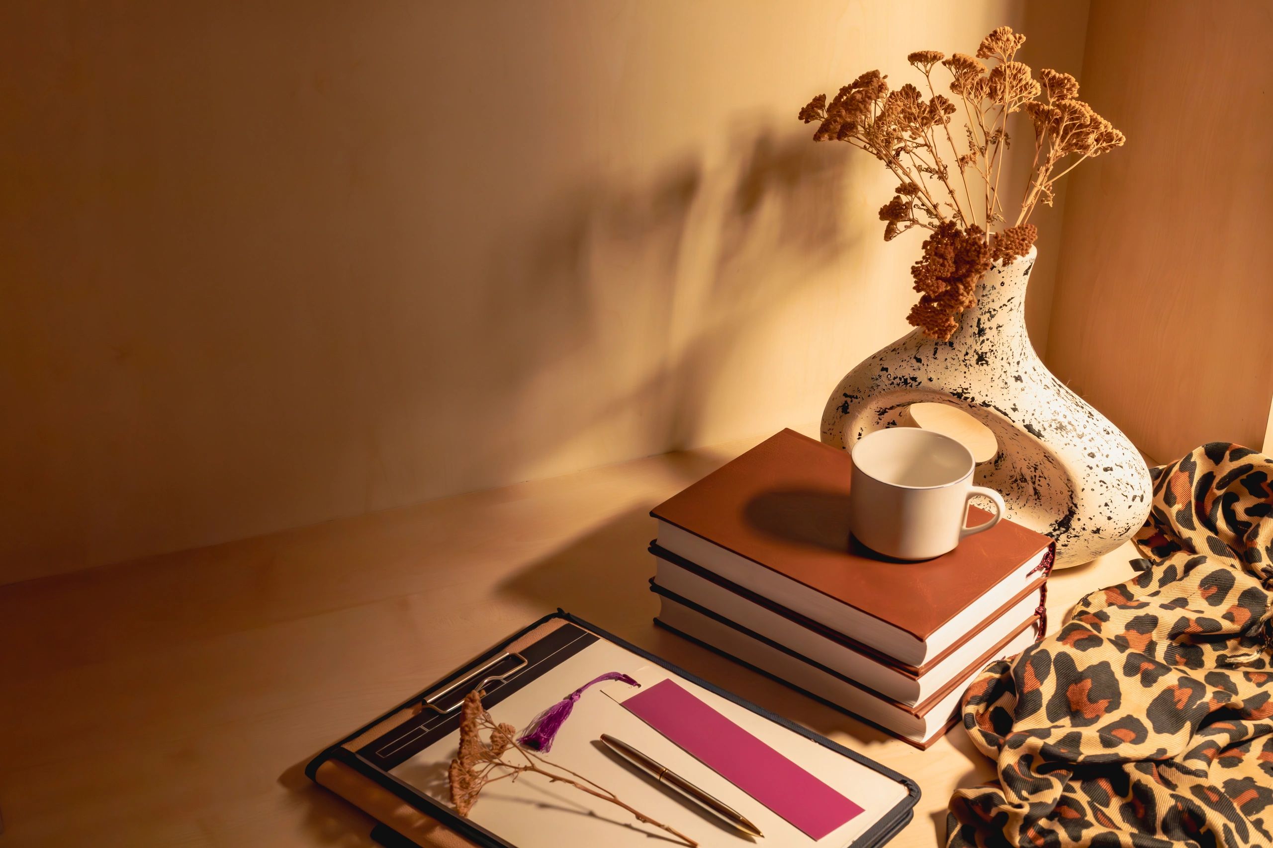 Editorial still life with books, coffee, and dried flowers on a reading table